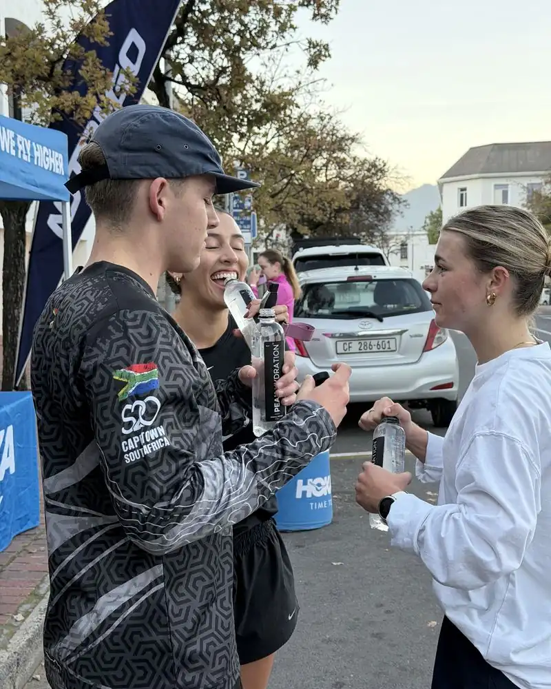Runners sharing Peak Hydration at a race-day stand