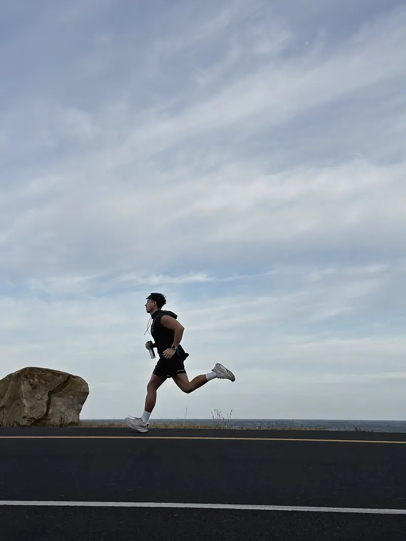 A runner mid-stride on a coastal road under an open sky